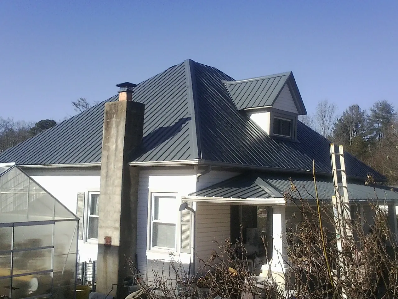 Dark blue standing seam metal roof on a white farmhouse with dormer — Slate & Tile Roof Repair by Roofing Brothers in Kings Mills
