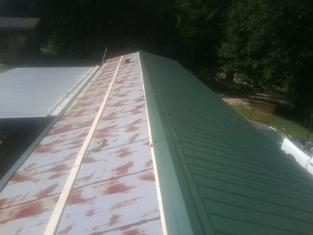 Old rusted panels beside newly installed green metal roofing — Wind Damage Roof Repair by Roofing Brothers in Kings Mills