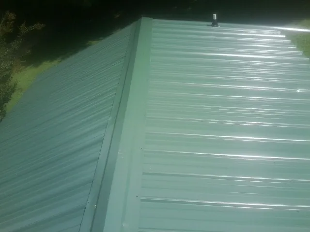 New green metal panels meeting at the ridge of a roof — Flat Roof Repair work by our crew in Kings Mills