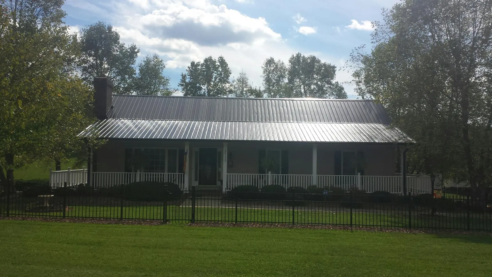 Gray metal roof on a brick ranch with a full width front porch — Gutter Guard Installation work by our crew in Kings Mills