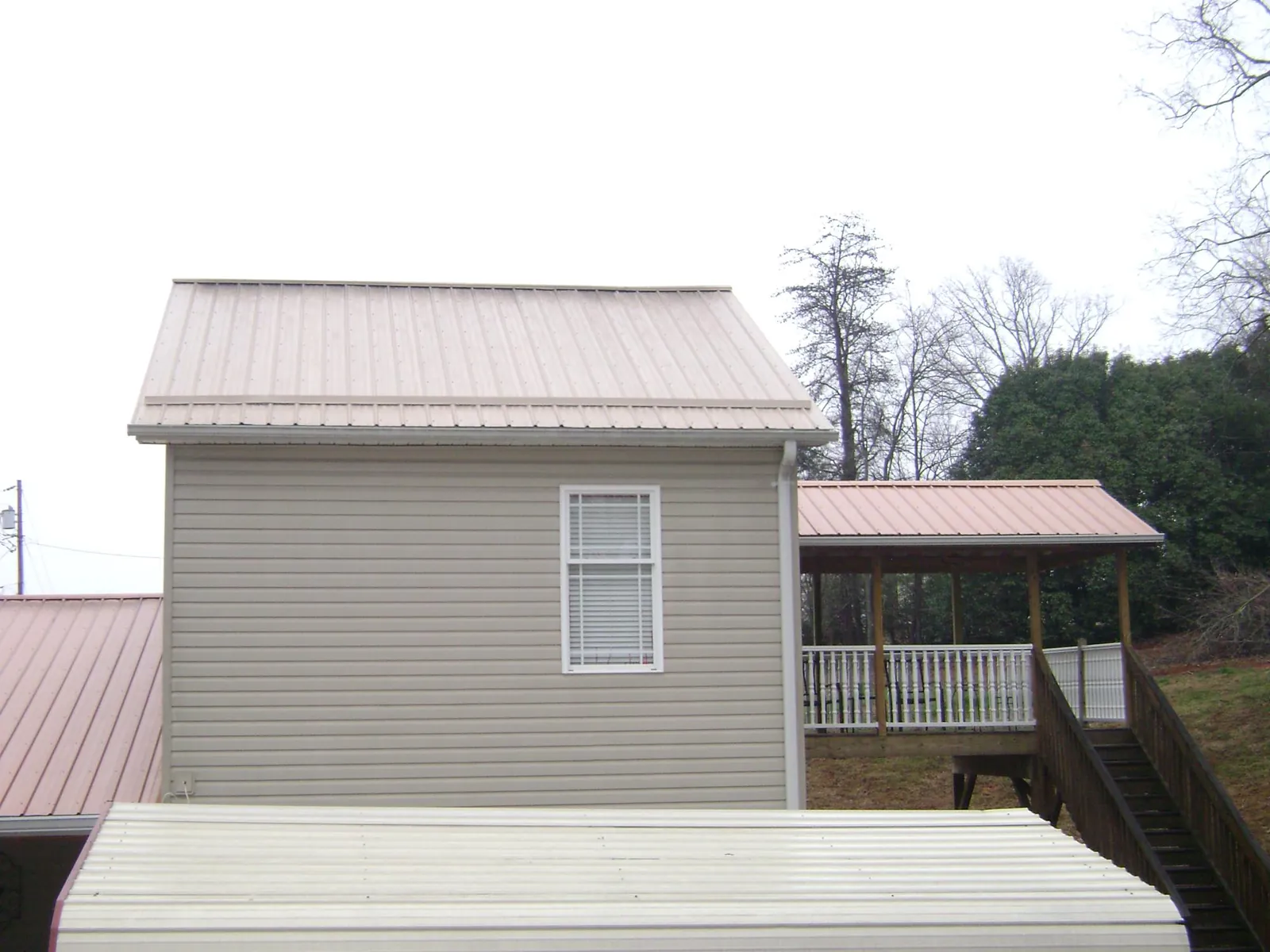 Tan metal roofs on a two story addition and attached porch, from a Roof Replacement job in Kings Mills