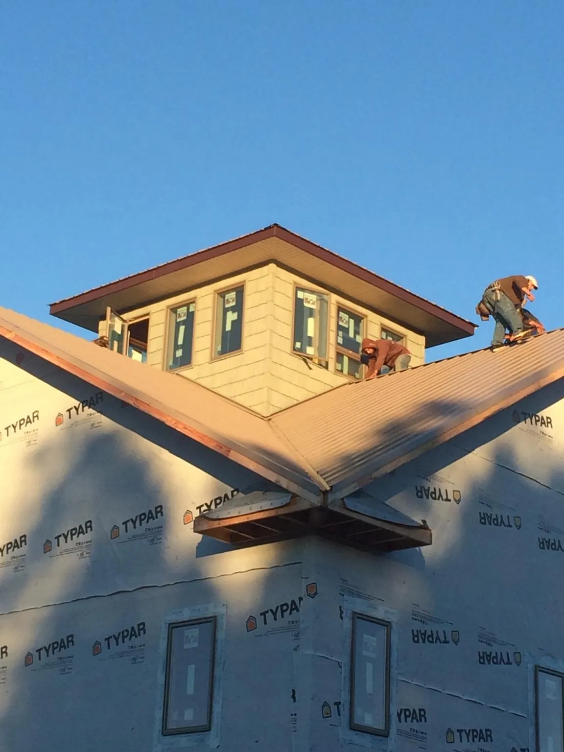 Roofers working around a rooftop cupola on a new metal roof at sunset — Roof Waterproofing in Kings Mills by Roofing Brothers